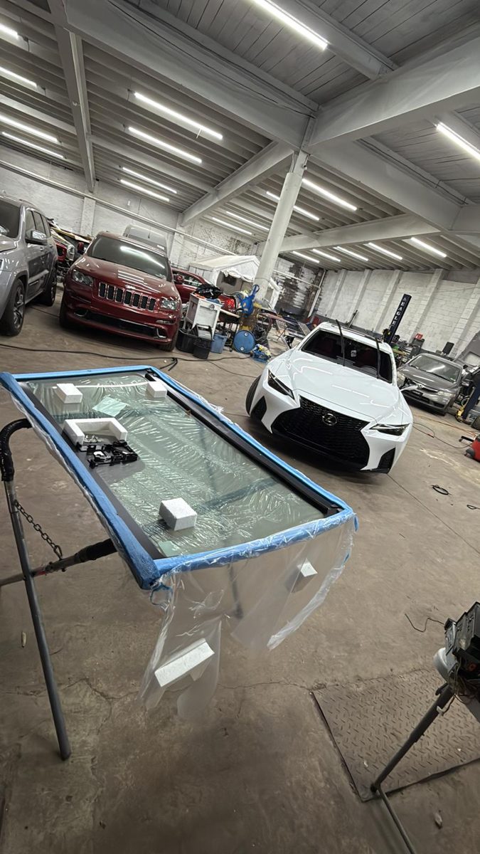 New windshield prepped on a stand next to the Lexus