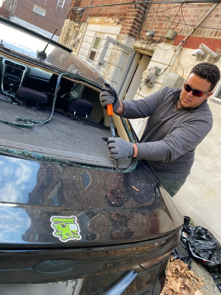 Technician clearing shattered back glass from a Ford